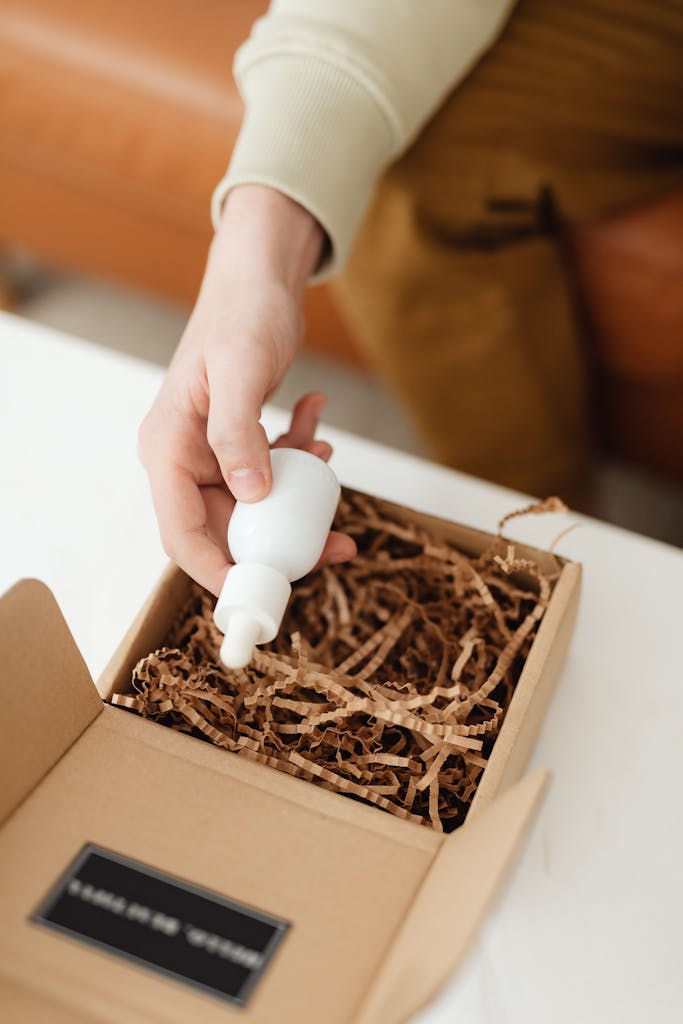 Person holding a white dropper bottle inside recyclable packaging – sustainable beauty concept