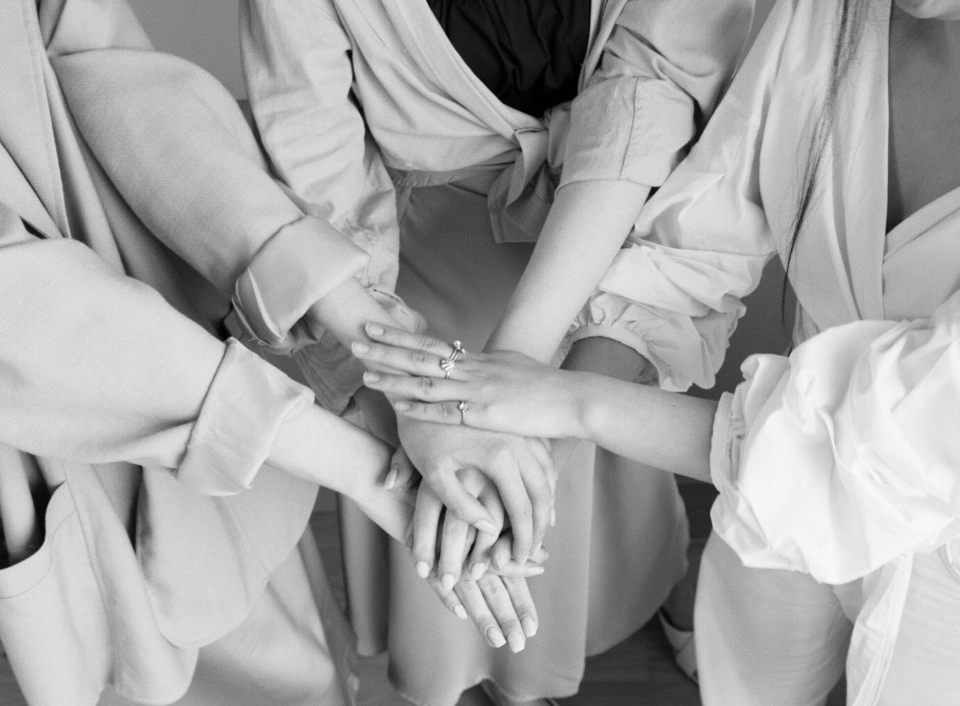 three women putting their hands together in the middle