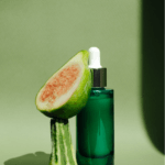 A green-tinted glass serum bottle and a slice of guava