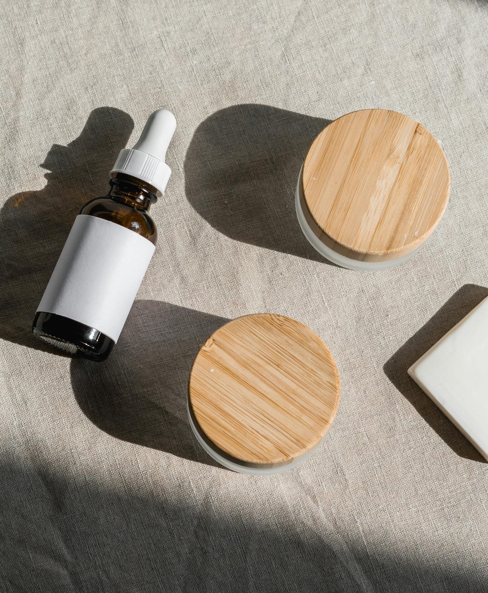 Minimalist skincare containers on a gray background, representing sustainable beauty packaging.