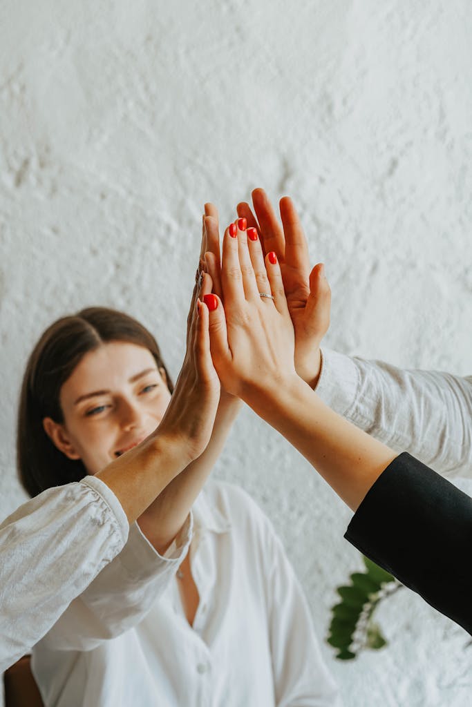 Group of people giving a high five, symbolizing teamwork and cooperation around a sustainability strategy, with a smiling woman in the background.