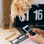 Woman calculating sustainability metrics on a smartphone in a modern office setting.