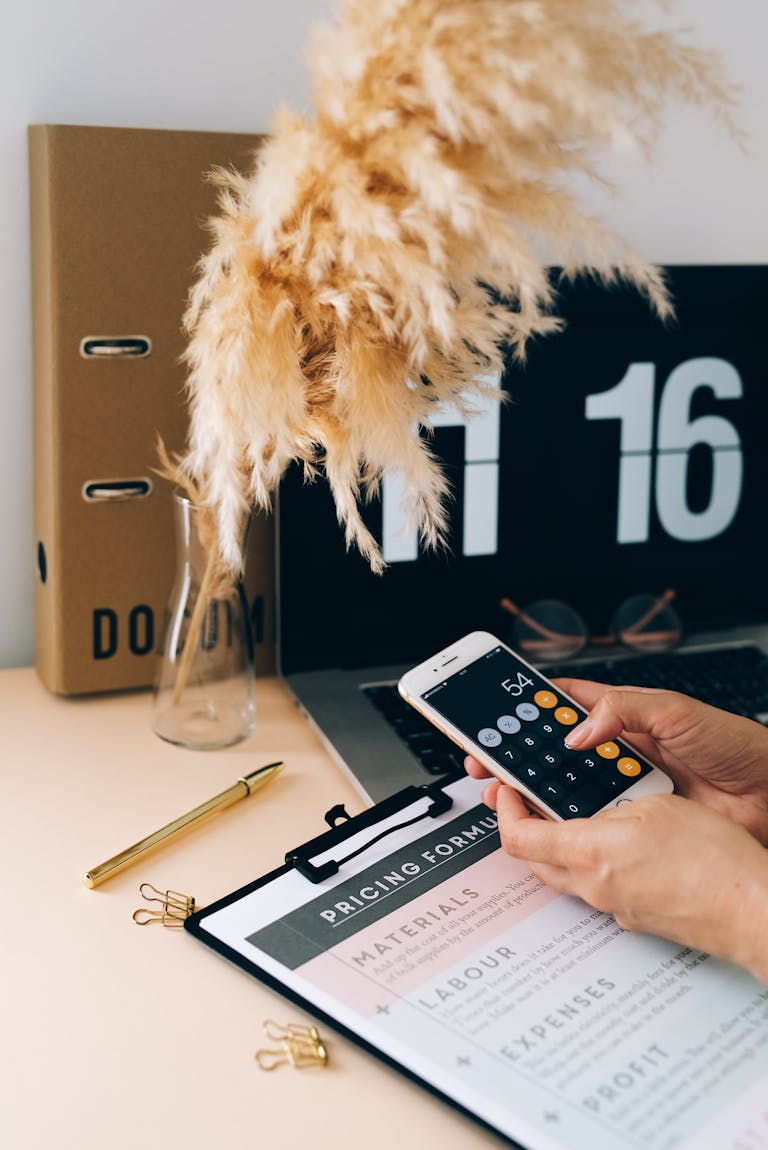 Woman calculating sustainability metrics on a smartphone in a modern office setting.
