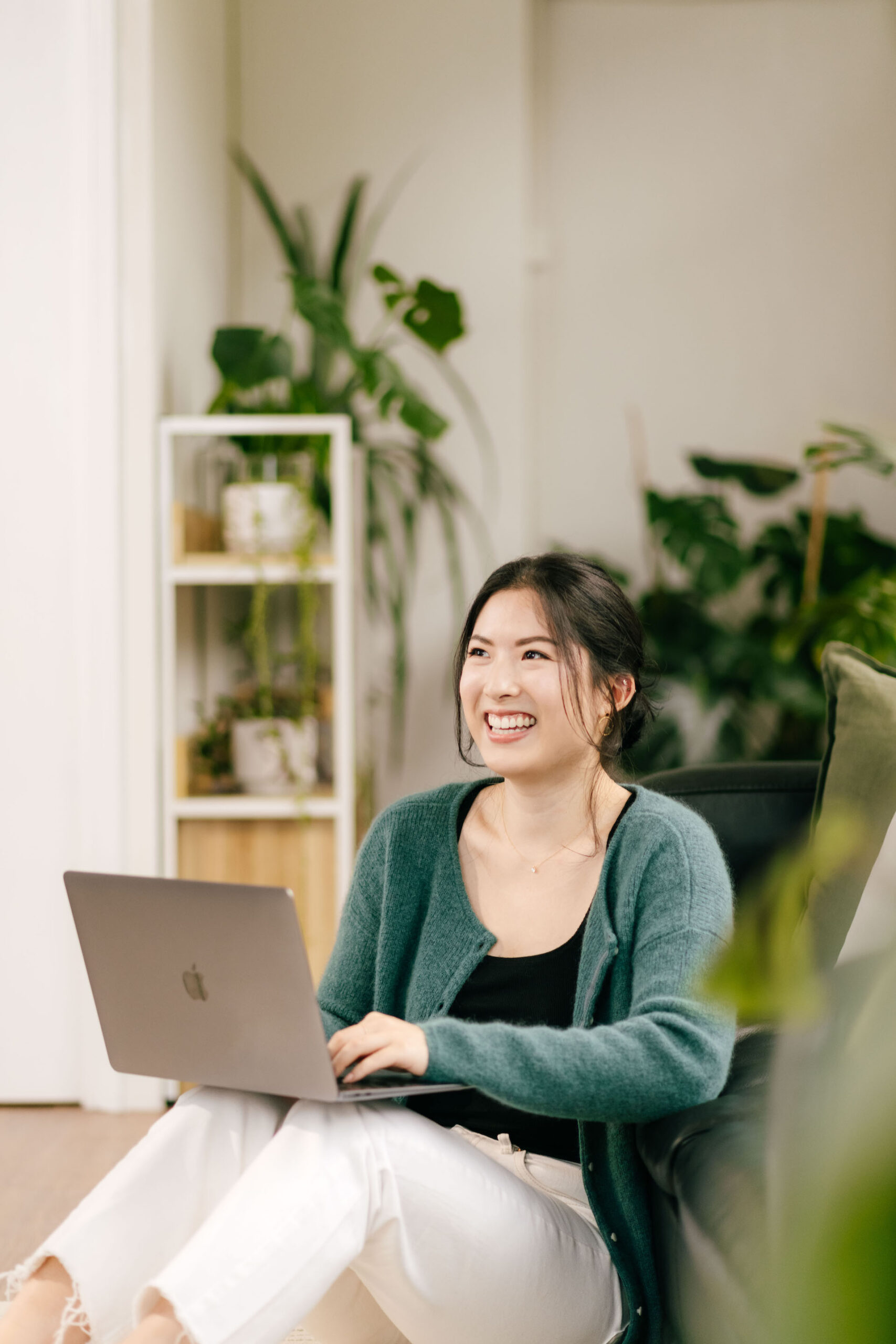Woman looking up while sitting on the floor with a laptop resting on her knees.