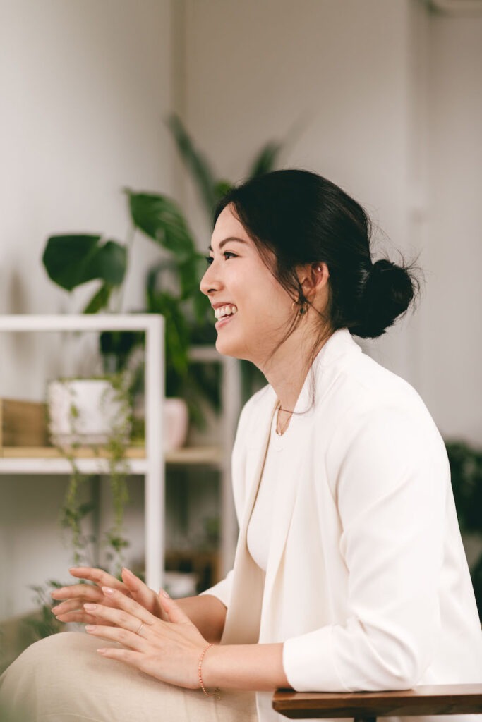 Woman sitting on a chair talking to a client with her hands resting on her lap.